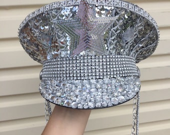 May include: A silver sequined and rhinestone-encrusted hat with a star design and a chain attached.