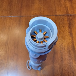 Puede incluir: Una vista cercana del interior de un objeto gris impreso en 3D. El objeto tiene una abertura circular que revela una bobina de color cobre.