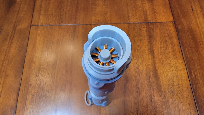 Puede incluir: Una vista cercana del interior de un objeto gris impreso en 3D. El objeto tiene una abertura circular que revela una bobina de color cobre.