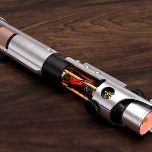 May include: A silver lightsaber with a black handle and a red glowing blade. The lightsaber is disassembled, revealing the internal workings.