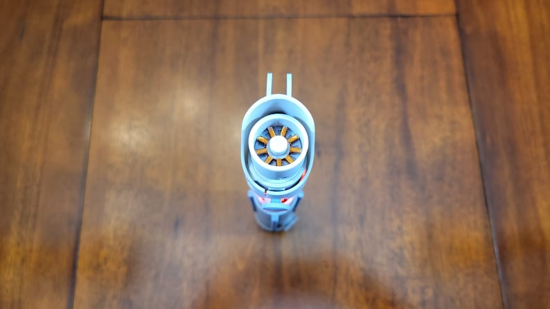 May include: A white and silver lightsaber with a gold and orange engine visible inside the hilt.