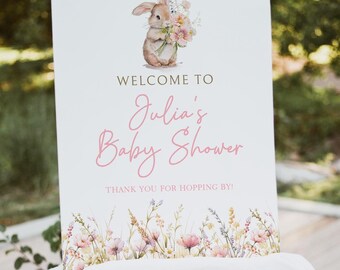 Könnte beinhalten: Ein weißes Schild mit einer Aquarell-Illustration eines Hasen, der einen Blumenstrauß hält. Auf dem Schild steht "Willkommen zu Julias Baby Shower! Danke, dass du vorbeikommst!"