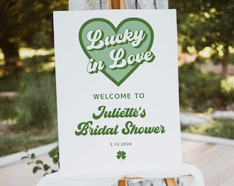 Könnte beinhalten: Ein weißes Schild mit grünem Text und einem grünen Herzen, auf dem "Lucky in Love" und "Willkommen zu Juliettes Bridal Shower 3.12.2024" steht. Das Schild steht auf einem Holzstaffelei.