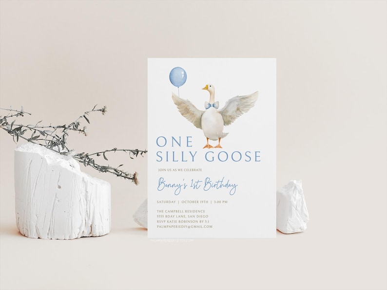 Op de afbeelding: Een blauwe en witte verjaardagsuitnodiging met een aquarel-illustratie van een gans die een blauwe strik draagt en een blauwe ballon vasthoudt. De tekst luidt "One Silly Goose" en "Bunny's 1st Birthday".