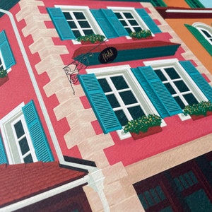 Detail view of an art print depicting the colourful buildings of Alsace, France, adorned with flowers on a cobble stone street.