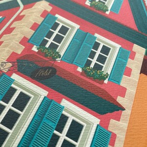 Detail view of an art print depicting the colourful buildings of Alsace, France, adorned with flowers on a cobble stone street.