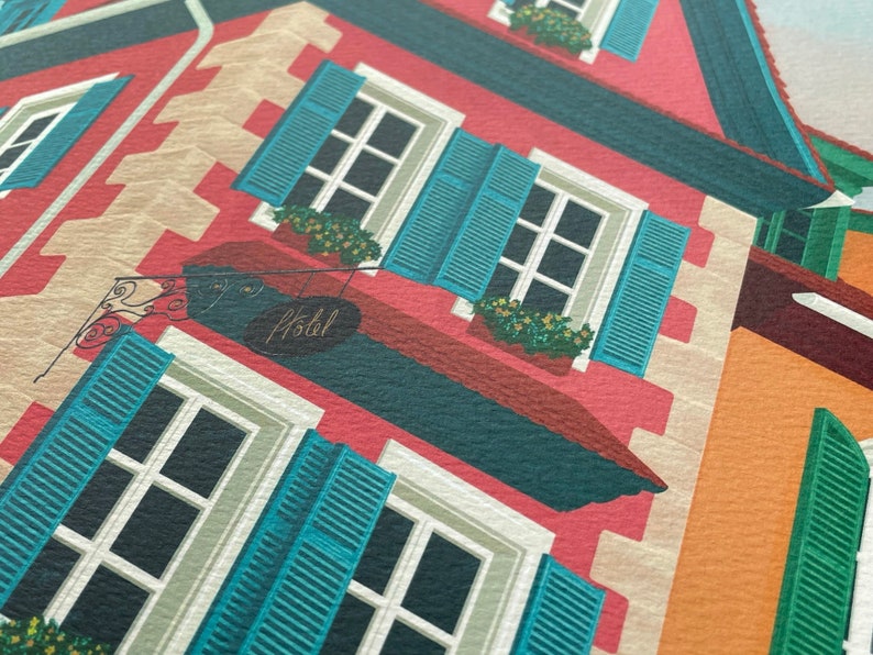 Detail view of an art print depicting the colourful buildings of Alsace, France, adorned with flowers on a cobble stone street.