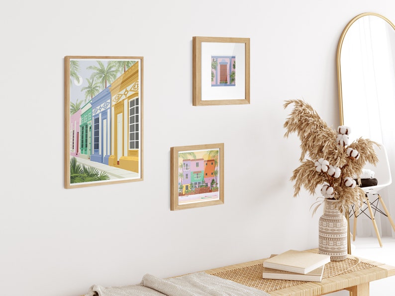 A collection of Venezuelan art prints in the form of a gallery wall featuring a beach, a colonial style window and houses in Maracaibo.