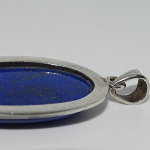 Op de afbeelding: Een zilveren hanger met een blauwe ovale lapis lazuli-steen.