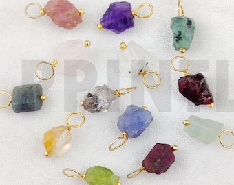 Può includere: Assortimento di 12 ciondoli in pietra grezza con anelli a salto placcati oro. Le pietre preziose includono ametista, acquamarina, citrino, granato, peridoto, quarzo rosa, rubino, zaffiro, quarzo affumicato e topazio.