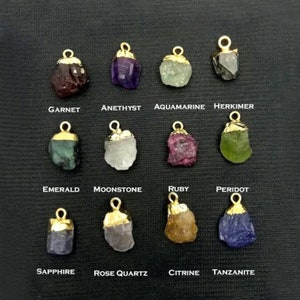 May include: Twelve gold-plated pendants with different colored gemstones, including garnet, amethyst, aquamarine, herkimer, emerald, moonstone, ruby, peridot, sapphire, rose quartz, citrine, and tanzanite.