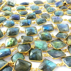 May include: A long necklace made of faceted labradorite stones set in gold-toned metal. The stones are a mix of dark green, blue, and grey with iridescent flashes.