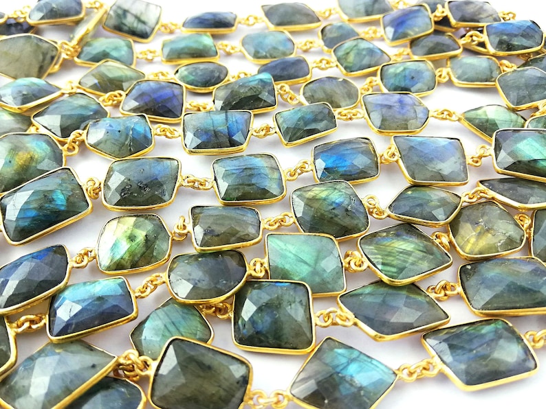 May include: A long necklace made of faceted labradorite stones set in gold-toned metal. The stones are a mix of dark green, blue, and grey with iridescent flashes.