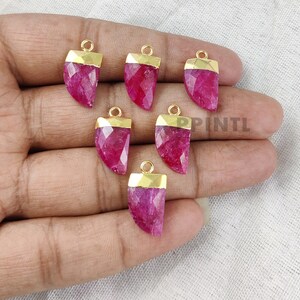 Può includere: Sette ciondoli in pietra preziosa rosa con montature placcate oro. I ciondoli hanno la forma di un dente o di una zanna affilata.