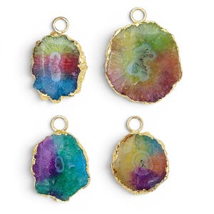 May include: Four irregular, translucent agate slice pendants featuring vibrant, multi-coloured rainbow patterns. Each stone is encased in a textured gold-tone metal rim and includes a small circular gold-tone jump ring at the top for attachment.