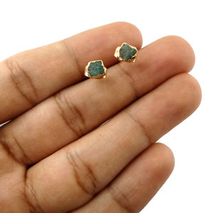 Puede incluir: Un par de pendientes de oro con piedras de esmeralda verde. Las piedras son ásperas y tienen un aspecto natural y sin pulir.