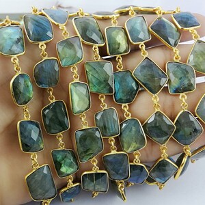 May include: A gold chain with multiple strands of faceted labradorite gemstone beads. The beads are a dark green color with iridescent flashes of blue and gold.