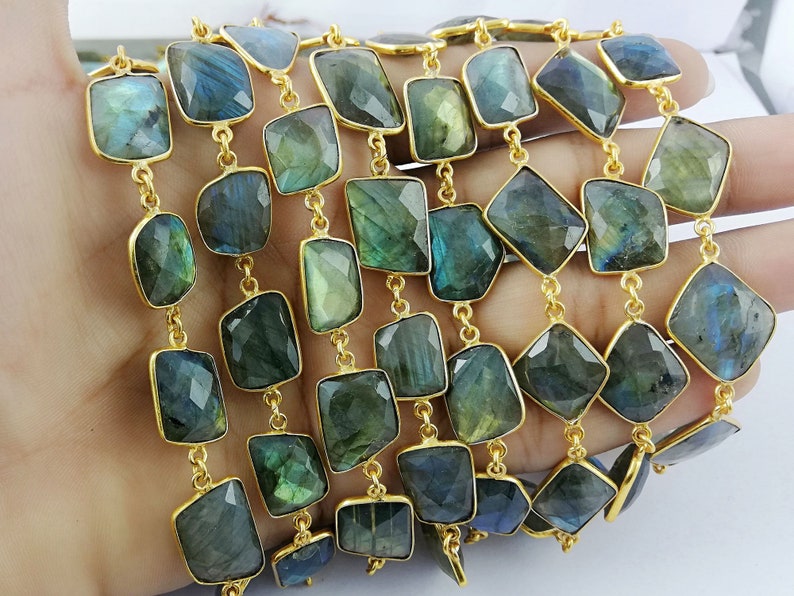May include: A gold chain with multiple strands of faceted labradorite gemstone beads. The beads are a dark green color with iridescent flashes of blue and gold.