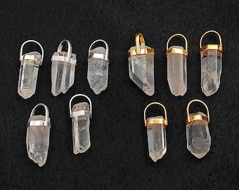 May include: Nine clear quartz crystal pendants with silver and gold-colored metal caps and loops. The crystals vary in shape and size, with a natural, rough texture. The pendants are displayed against a black background.