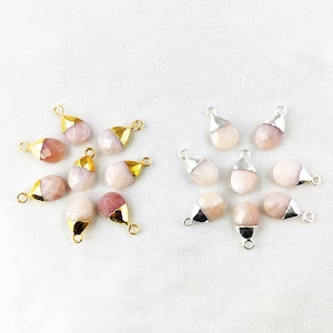 May include: A collection of pink and white gemstone pendants with gold and silver accents. The pendants are shaped like teardrops and have a smooth, polished finish.