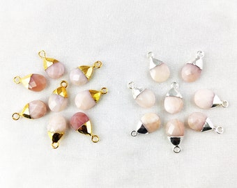 May include: A collection of pink and white gemstone pendants with gold and silver accents. The pendants are shaped like teardrops and have a smooth, polished finish.