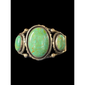 May include: A silver cuff bracelet featuring three oval turquoise stones. The stones are a vibrant green with brown veining, set in ornate silver bezels. The bracelet has a classic Southwestern design.