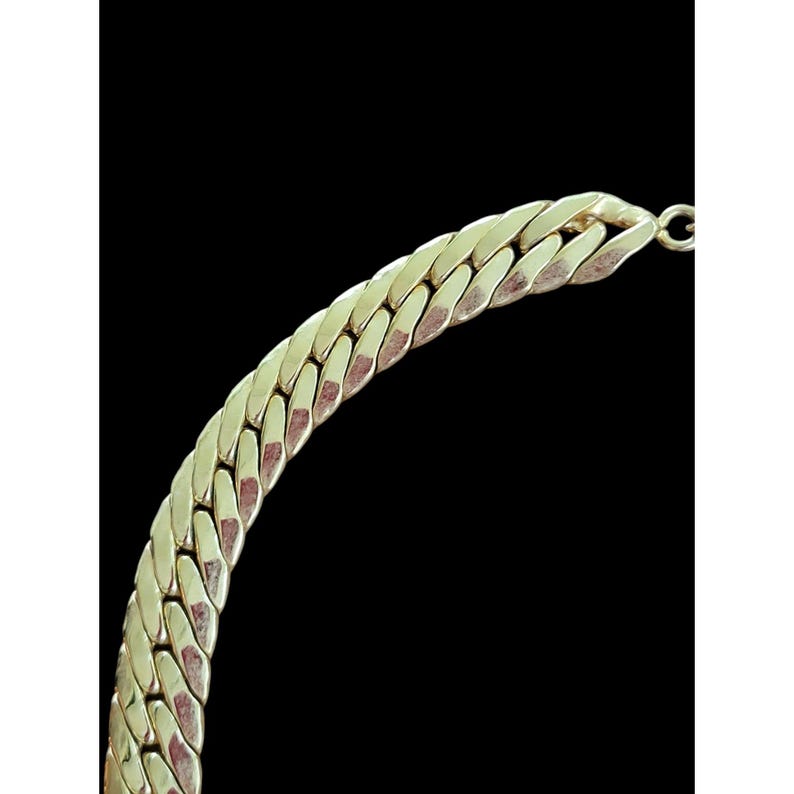 May include: A gold chain necklace with a thick, chunky curb link design.