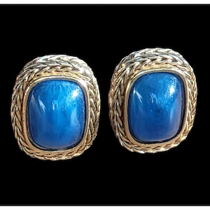 Puede incluir: Un par de pendientes de tono dorado con piedras de vidrio azul engastadas en un diseño tejido.