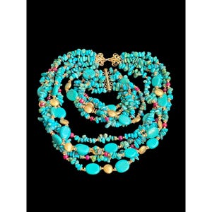 May include: A multi-strand necklace and matching bracelet set featuring turquoise chips, smooth turquoise oval beads, small round gold-tone beads, and small round magenta beads. The jewellery pieces are secured with ornate gold-tone metal clasps.