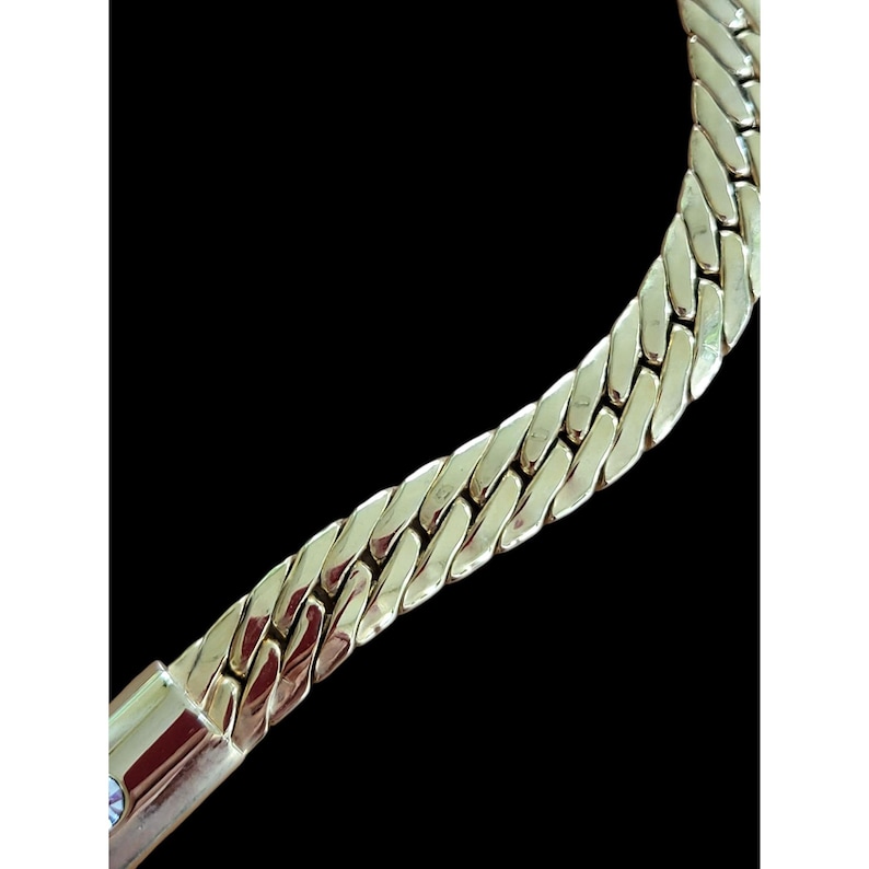 May include: A gold chain necklace with a thick, textured, curb link design.