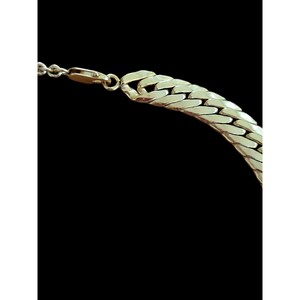 May include: A gold chain necklace with a curb link design. The chain is thick and has a shiny finish.