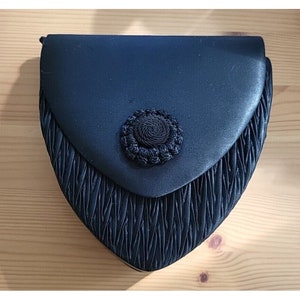 May include: A black satin heart-shaped evening bag with a black and white circular button.
