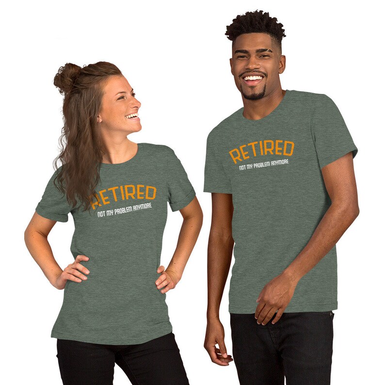 May include: Two people wearing green heather t-shirts with the text "Retired Not My Problem Anymore" in orange and white lettering.