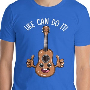 May include: A royal blue t-shirt with a white graphic of a ukulele with a smiling face and the text "UKE CAN DO IT!"