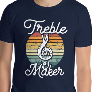 May include: A navy blue t-shirt with a vintage-style graphic of a treble clef and the text "Treble Maker".