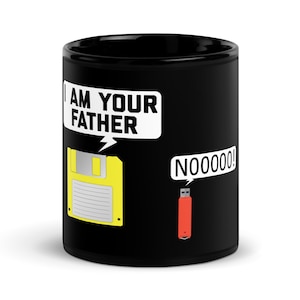 Puede incluir: Taza de café negra con un gráfico blanco de un disquete y una unidad USB. El disquete dice "Soy tu padre" y la unidad USB dice "Noooooo!"
