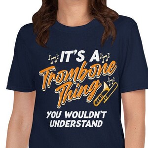 May include: Navy blue t-shirt with white text that reads "It's a Trombone Thing You Wouldn't Understand". The text is in a stylised font with musical notes and a trombone graphic.