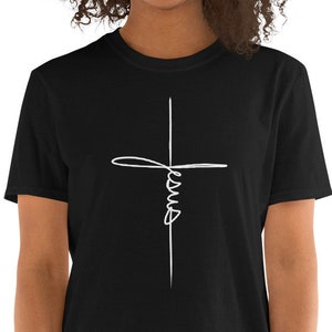 Peut inclure: Un t-shirt noir avec une croix blanche et le mot "Jésus" écrit en cursive.