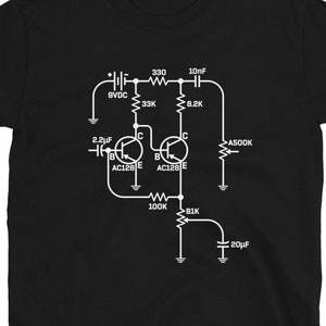 Può includere: T-shirt nera con un diagramma schematico bianco di un circuito elettronico. Il design include simboli di componenti come resistori e condensatori, con etichette come 9VDC, 33K e AC128 E. Un design unico per gli appassionati di elettronica.