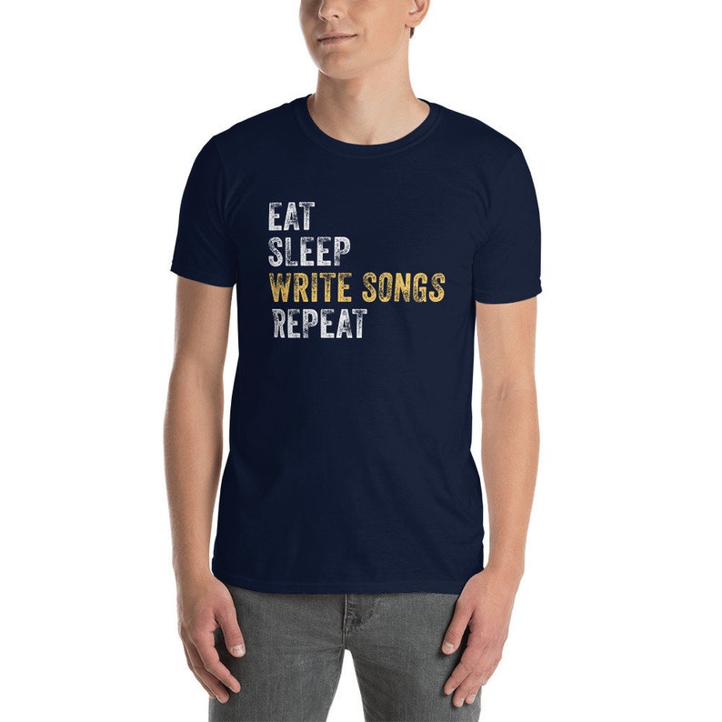 Puede incluir: Una camiseta azul marino con un gr&aacute;fico blanco desgastado que dice "Eat Sleep Write Songs Repeat".