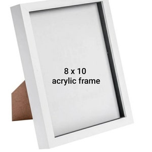 May include: White 8 x 10 inch acrylic picture frame with a black mat. The frame is standing on a wooden easel.