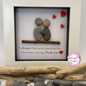 May include: A framed pebble art piece with two figures holding hands, surrounded by small red hearts. The text reads "Colleagues Like you are special and few. I Just want to say a big Thank you."