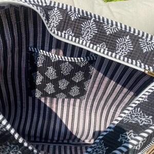 Pu&ograve; includere: Borsa tote aperta con motivo floreale bianco e nero e interno a righe. La borsa &egrave; dotata di chiusura con cerniera e di una piccola tasca con un motivo floreale abbinato. Il bordo della borsa &egrave; a righe bianche e nere.