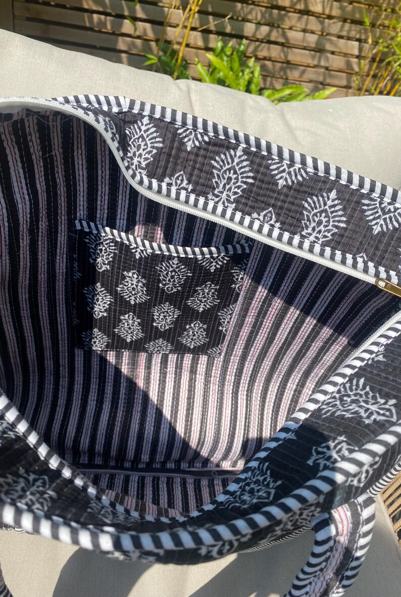 Pu&ograve; includere: Borsa tote aperta con motivo floreale bianco e nero e interno a righe. La borsa &egrave; dotata di chiusura con cerniera e di una piccola tasca con un motivo floreale abbinato. Il bordo della borsa &egrave; a righe bianche e nere.