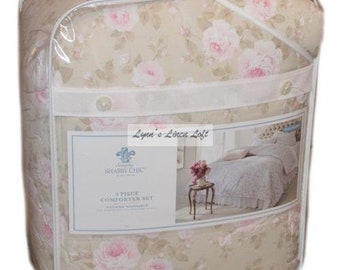 May include: A 3-piece comforter set in a beige and pink floral pattern. The comforter set is packaged in a clear plastic bag with a white label that says "Shabby Chic" and "3 Piece Comforter Set".