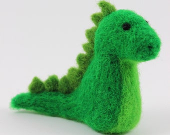 May include: A green felt dinosaur toy with a spiky back and a long tail.