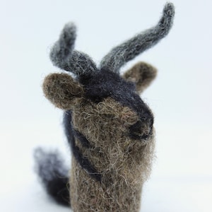 Może przedstawiać: Mały, brązowo-czarny zwierzę z długimi, szarymi rogami z filcu. Zwierzę ma czarny filcowy nos i usta.