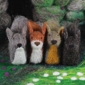 May include: Four felt animal figurines, a gray squirrel, a red squirrel, a brown squirrel, and a black squirrel, standing in a row on a green background with white flowers.