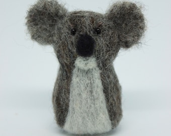 Può includere: Un piccolo giocattolo di koala in feltro grigio e bianco con occhi neri e naso nero.