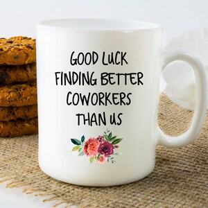 Peut inclure: Une tasse &agrave; caf&eacute; en c&eacute;ramique blanche avec du texte noir qui dit "Bonne chance pour trouver de meilleurs coll&egrave;gues que nous". Le texte est entour&eacute; d'un motif floral avec des fleurs roses et rouges.